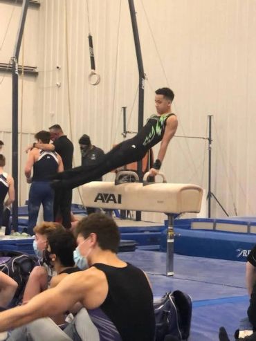 Young gymnast performing on pommel horse in a gymnasium.