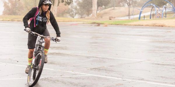 Person riding a bike on a wet pavement with colorful socks.