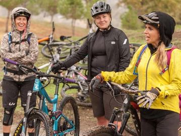 Three women cyclists chatting outdoors with their bikes.
