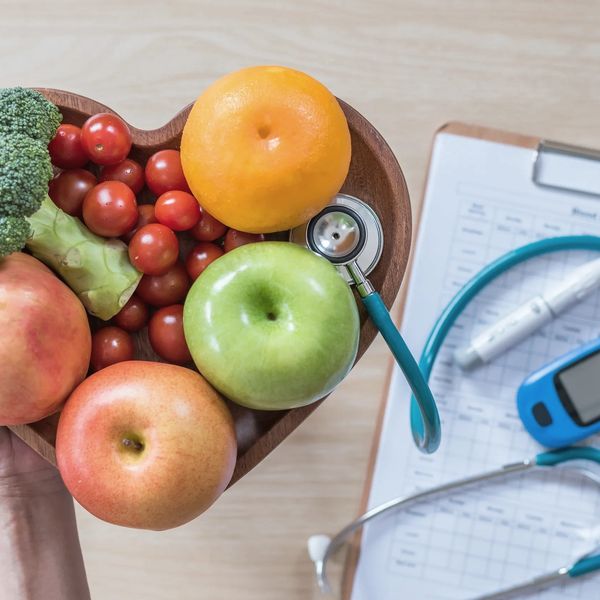 Heart shaped tray with fruits and vegetables next to a stethoscope and blood glucose monitor