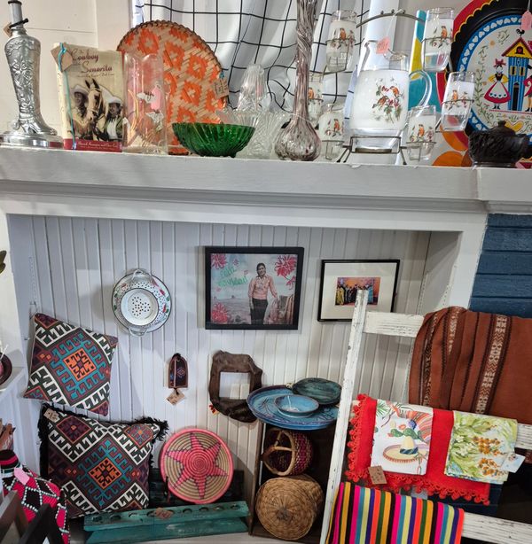 Colorful handmade textiles, woven baskets, and pottery displayed in a cozy shop corner.