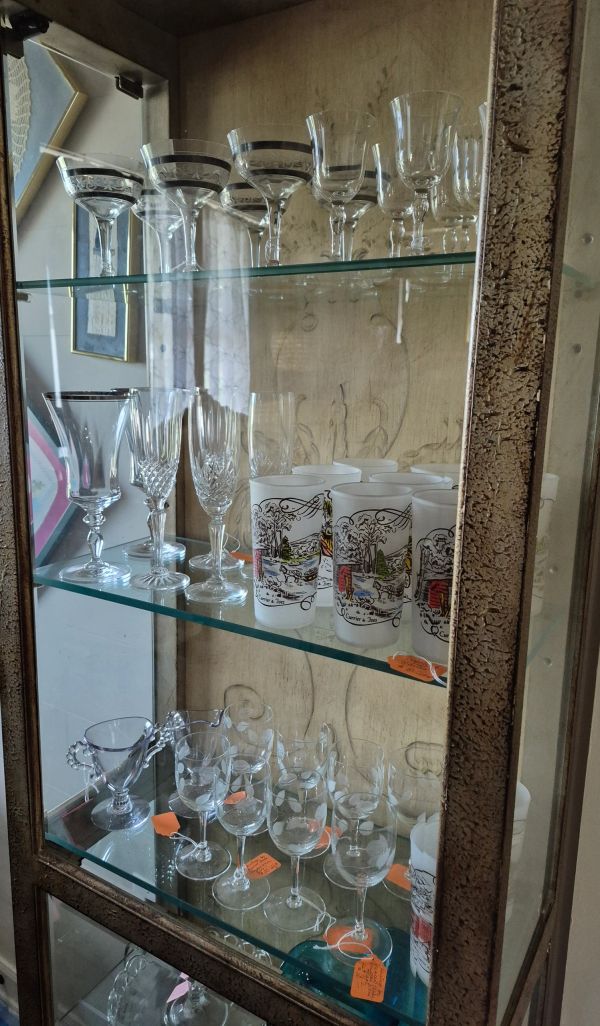 A vintage glass cabinet filled with various decorative glasses and goblets.