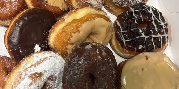Assorted donuts with various glazes and toppings in a box.