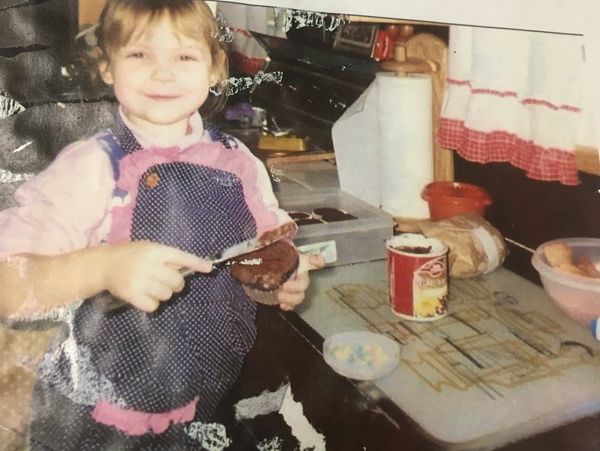 A young child spreading chocolate on a slice of bread in a cozy kitchen.