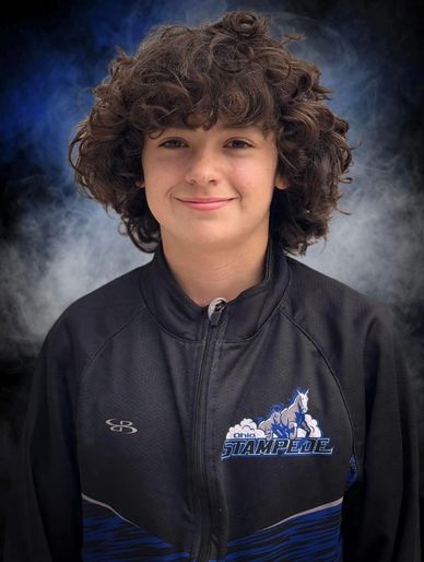 Smiling boy with curly hair in sports jacket.