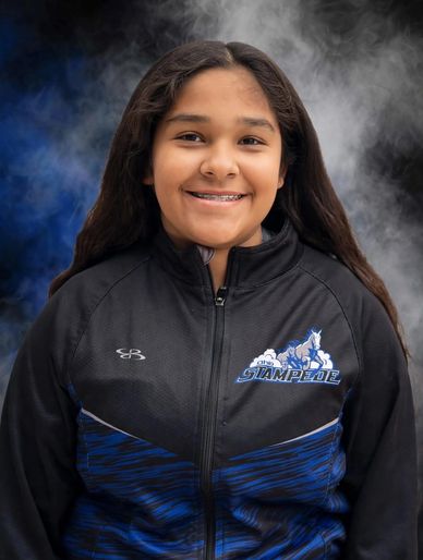 Smiling girl in a black and blue Stampede jacket.