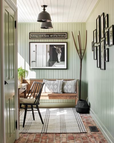 Mudroom with green beadboard walls, brick floors, and wooden bench. 