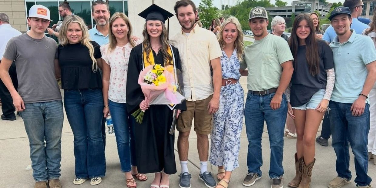 Group photo celebrating a graduation with a graduate in the center.