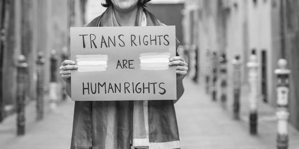 Person holding a sign that reads: "Trans Rights are Human Rights"