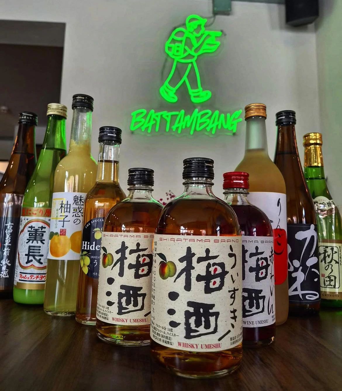 Assorted bottles of umeshu and sake on a wooden table.