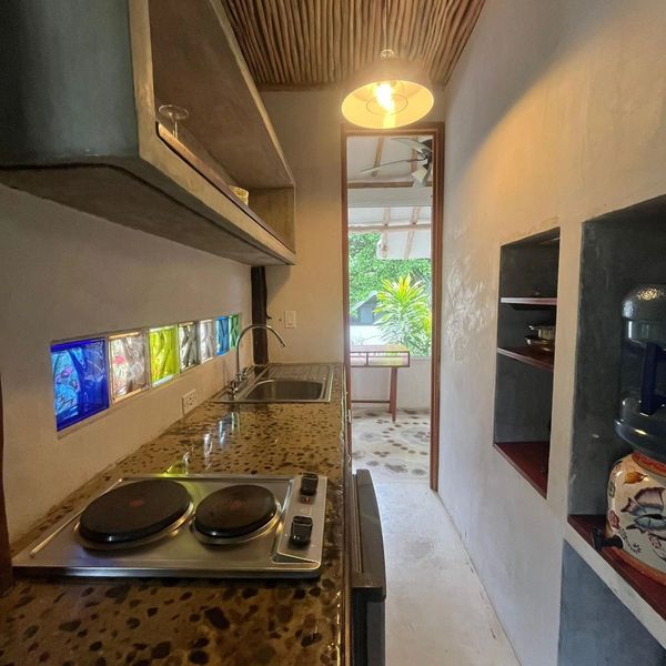 Compact kitchen with colorful glass tiles and natural light.