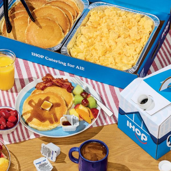 IHOP catering with pancakes, scrambled eggs, bacon, fruit, coffee, and orange juice.