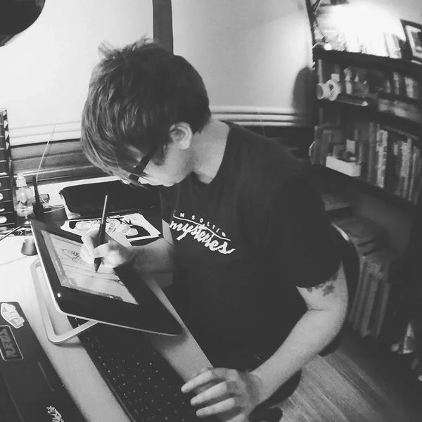 Person drawing on a digital tablet at their desk.