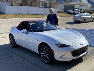 White Mazda convertible parked with a person standing behind it.