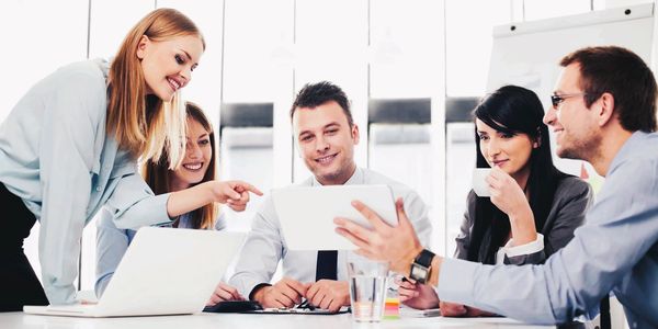 The Online Reputation Repair company team smiling while strategizing with at a table on computers.