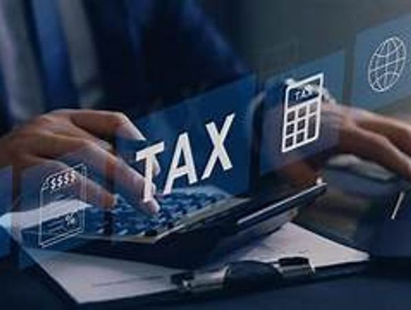 Person working on tax calculations using a laptop and calculator.