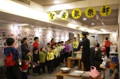 Children attentively listening to a man in a cultural or educational setting.