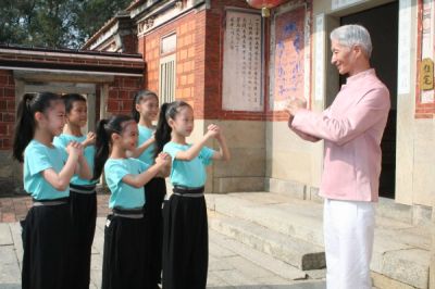 A group of children practicing martial arts with an instructor outdoors.