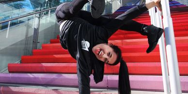 A professional dancer and acrobat performing a stunt near a stair