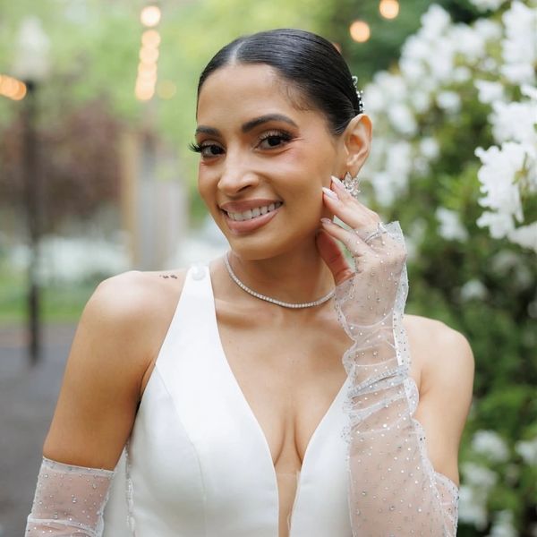 Smiling woman in elegant white dress with sheer gloves.