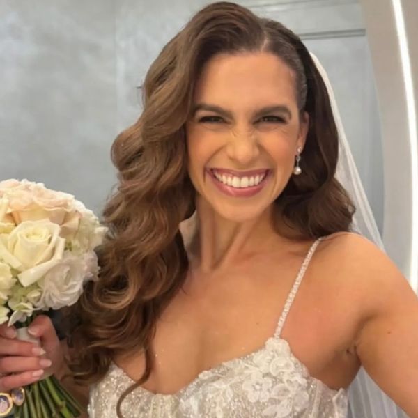 Bride smiling widely holding a bouquet of flowers.