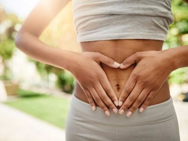 woman holding heart shape on stomach 