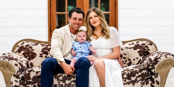 A happy family of three sitting on a patterned couch.