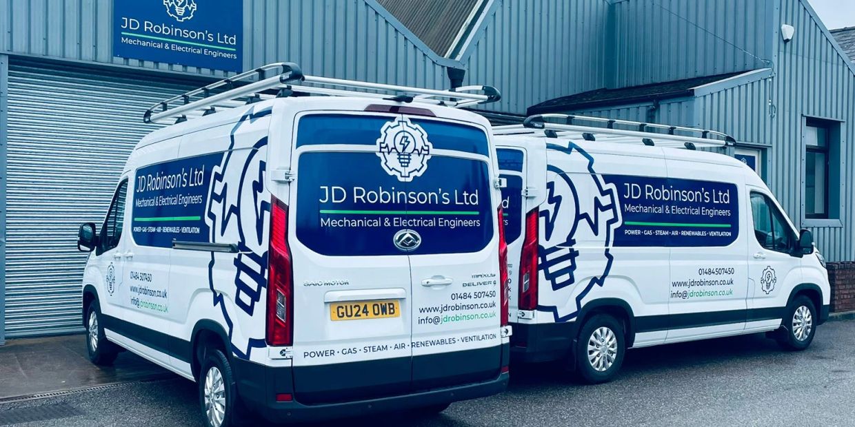 Two white company vans with JD Robinson's Ltd branding outside a workshop.
