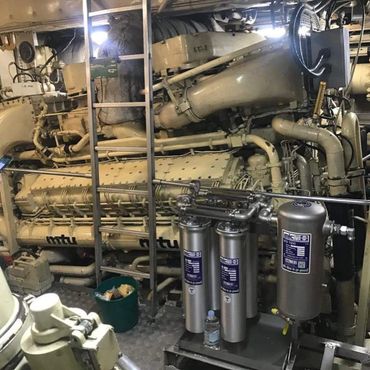 Large industrial engine with pipes and filters in a mechanical room.