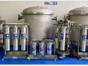 Industrial stainless steel filtration units arranged on a blue floor.