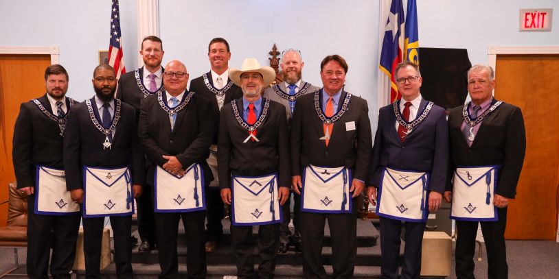 Group of men in formal attire with Masonic aprons and collars.