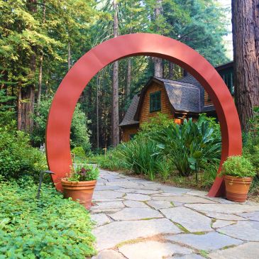 Red circular archway entrance to cabin in lush forest.