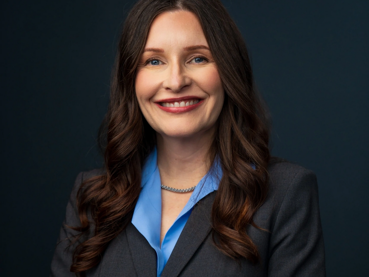 Confident woman with curly long brown hair smiling.