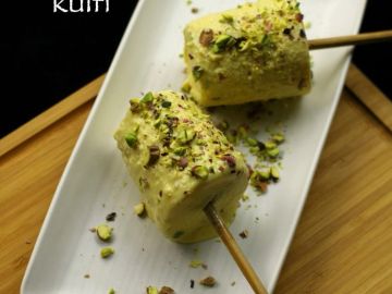 Two pistachio kulfi sticks garnished with crushed pistachios served on a white plate.