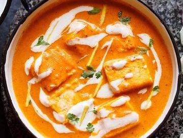 Creamy paneer butter masala garnished with cream and cilantro.