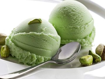 Two scoops of green pistachio ice cream with a spoon.