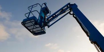 Blue aerial lift platform raised against a cloudy sky.