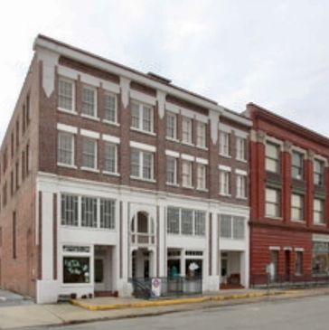 Historic multi-story brick buildings with large windows on a city street.
