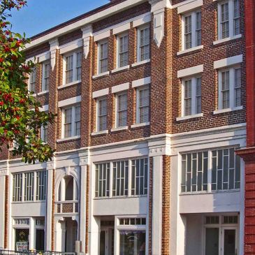 A historic brick building with white accents and large windows under a clear blue sky.