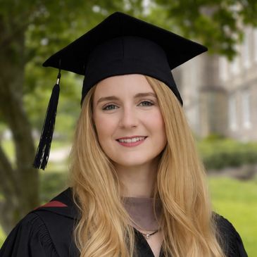 Young woman smiling in graduation attire outdoors.