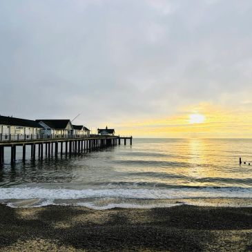 Sunset over the ocean with a pier extending into the water.