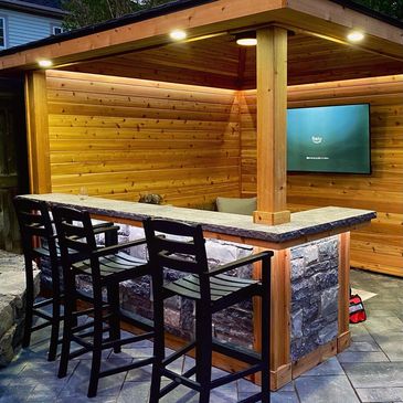 outdoor bar and gazebo with cedar and stone masonry, flatscreen tv, fridge, fan and lighting