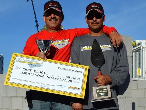 Two men celebrating winning a trowel competition with a trophy and a large check.