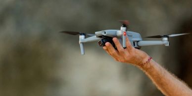 Hand holding a drone mid-flight.