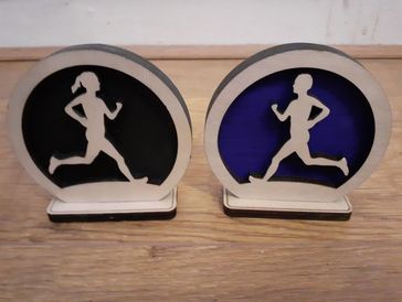Wooden running figure decorations, one black and one blue background.