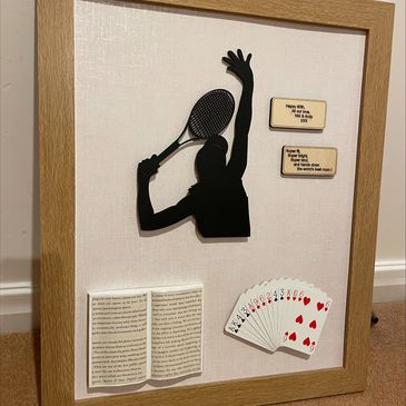 Framed tennis player silhouette with cards, book, and dedication plaques.