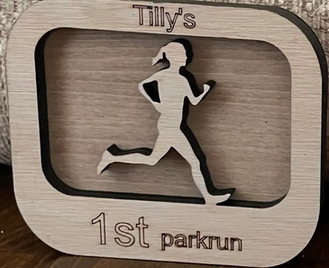 Wooden plaque celebrating Tilly's first parkrun with a running silhouette.