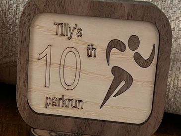Wooden plaque celebrating Tilly's 10th parkrun achievement.