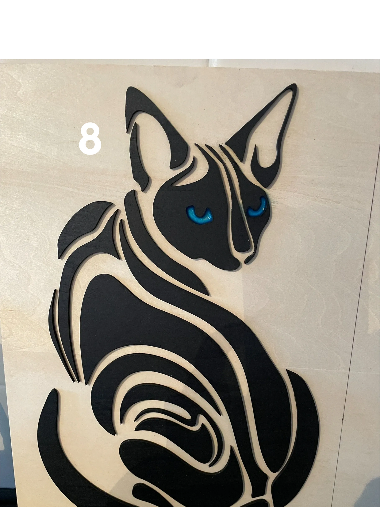 Abstract black cat silhouette with blue eyes on wood.
