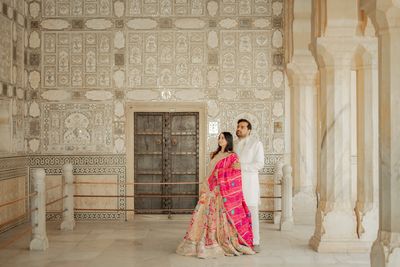 Couple in traditional attire posing in an ornate historic building.
